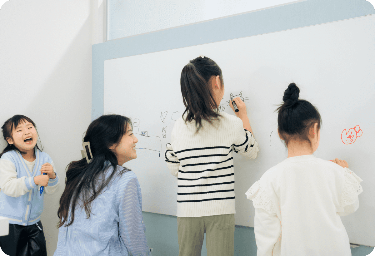 子どもたちがホワイトボードに絵を描きながら楽しそうに過ごしている様子